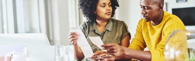 Woman and man sitting in front of a laptop, reviewing papers