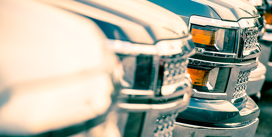 Front bumpers and headlights of a row of pickup trucks